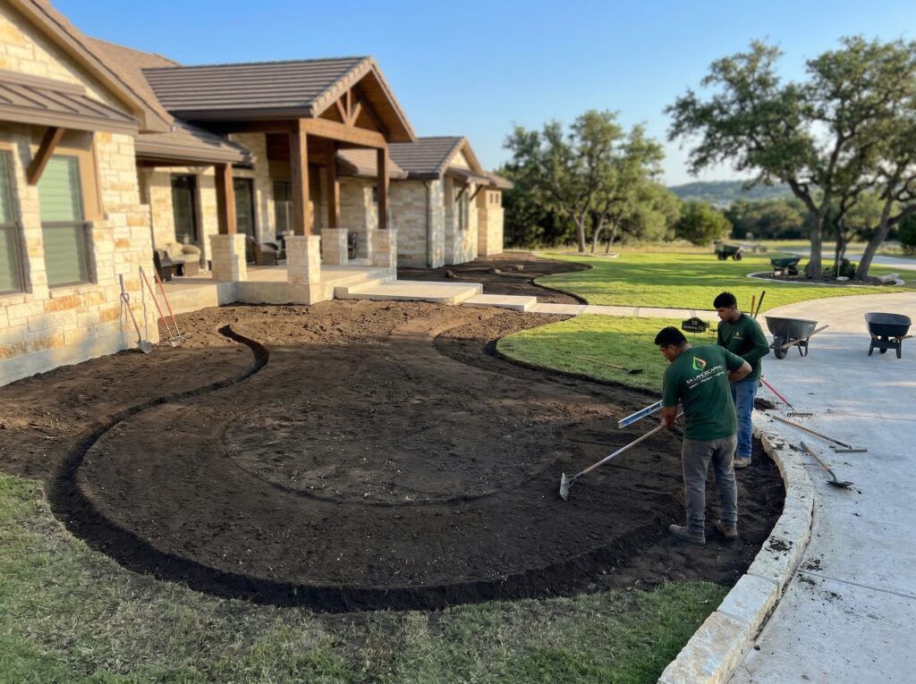 Landscaper shaping and grading landscape beds, checking level for clean edges and proper drainage in planter beds